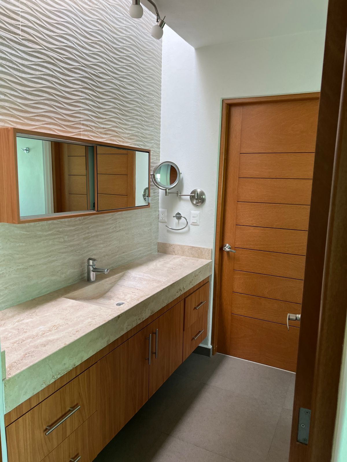 Baño con doble lavabo en travertino y mueble de madera