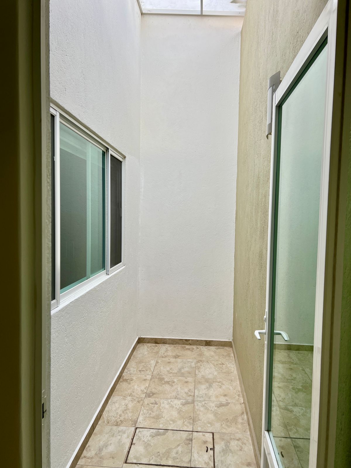 Patio interior con tragaluz y ventanas de cristal